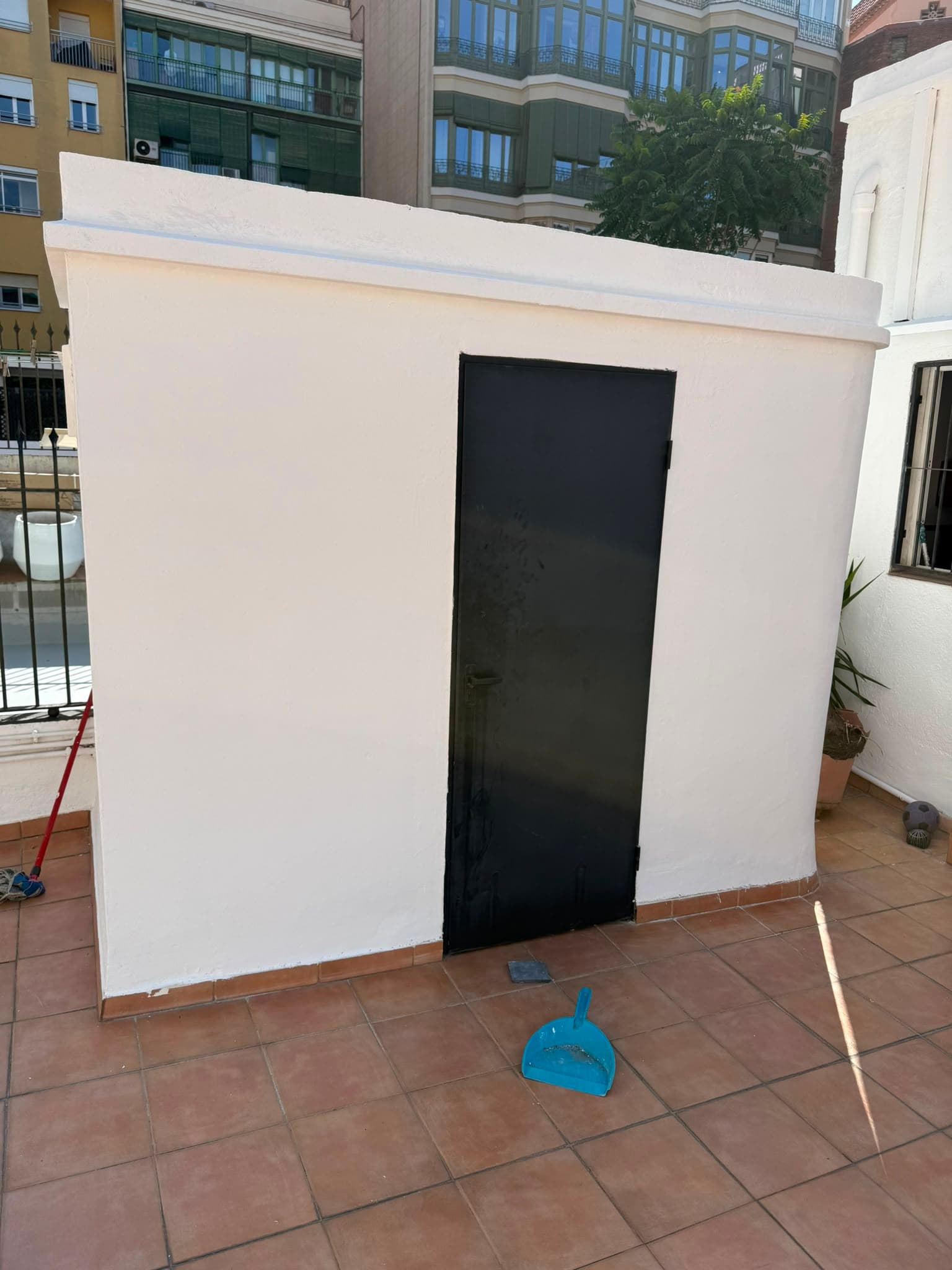 El mismo muro de terraza saneado, pintado en blanco y con la puerta metálica esmaltada en negro